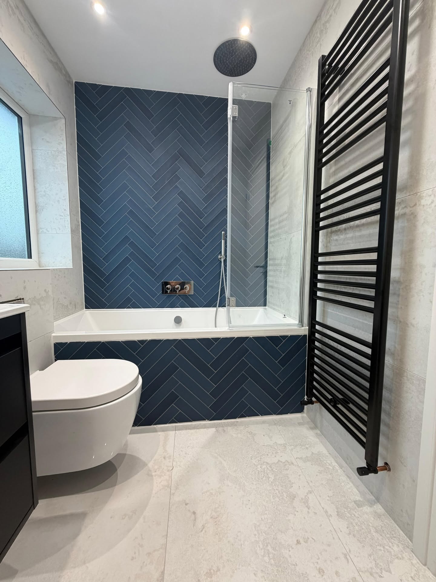 New bathroom with herringbone navy tile feature wall and freestanding bath by Ultra Build Northwest, Manchester